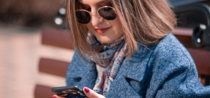 Lady with a sunglass wearing blazer looking at her phone