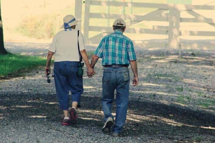 Older couple lovingly hold hands while walking.