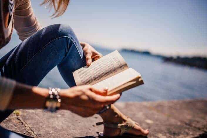 woman reading book in seashore