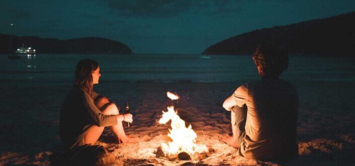 Man and woman sitting by a bonfire