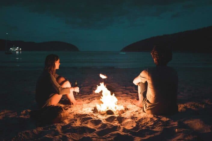 Two people talking to each other in front of a bonfire