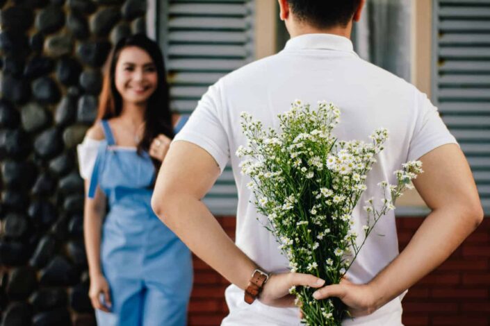Man keeping bouquet of flowers behind his back