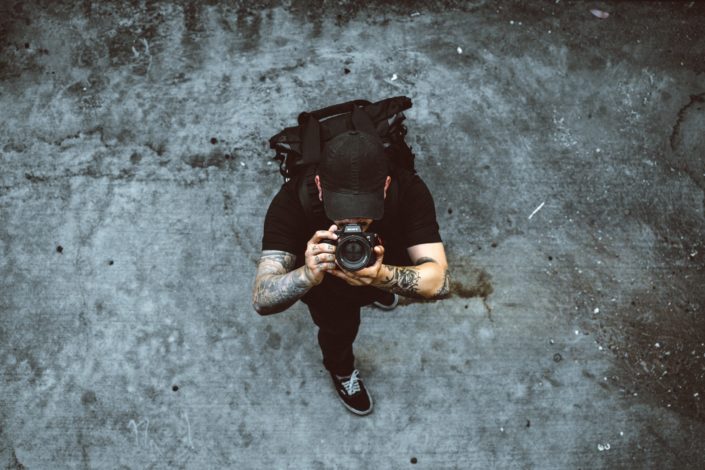 Man all dressed in black taking photos with his camera