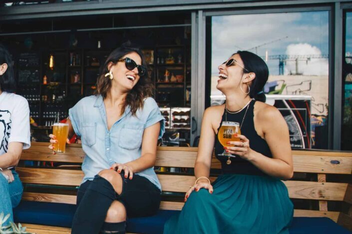 Smiling Women Sitting on Wooden Bench