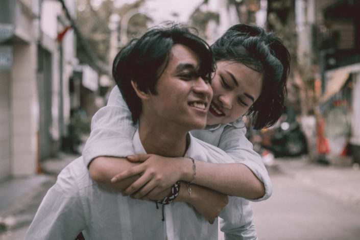 A man carrying a girl while they're both smiling