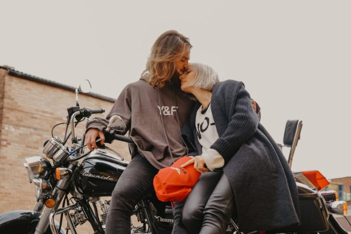 A man kissing a woman on the forehead while they're sitting on a motorcycle