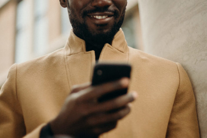 A man smiling at his phone while he's holding it