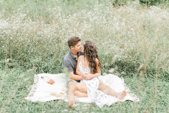 A couple about to kiss while sitting down in the middle of a field