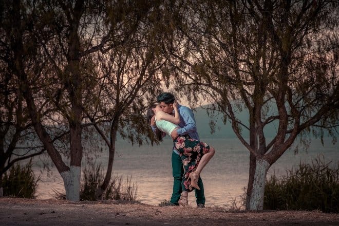 A Woman and a Man kissing underneath trees - Sweet Things To Do For Your Girlfriend