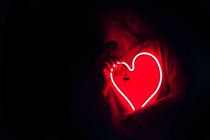 Heart-shaped neon lights held by a person