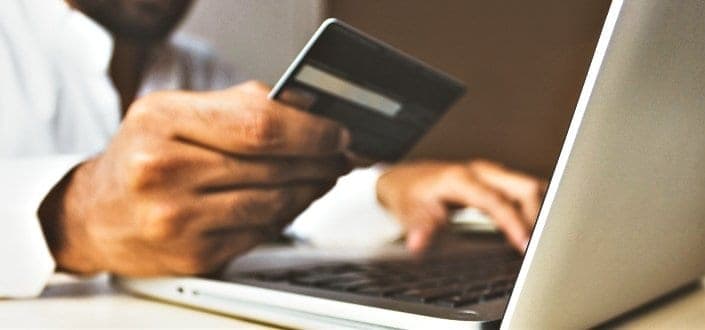 person using laptop and holding card