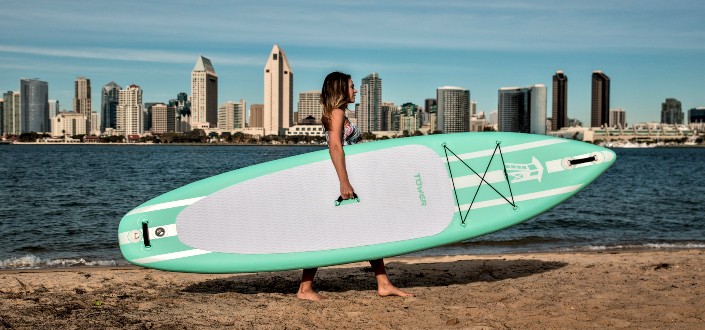 woman in bikini holding white surfboard on beach
