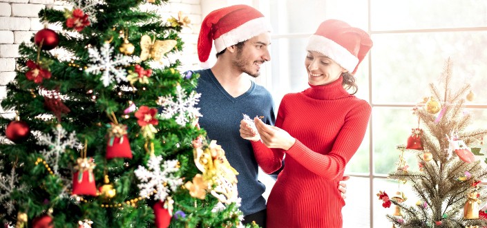 couple flirting while decorating their christmas tree
