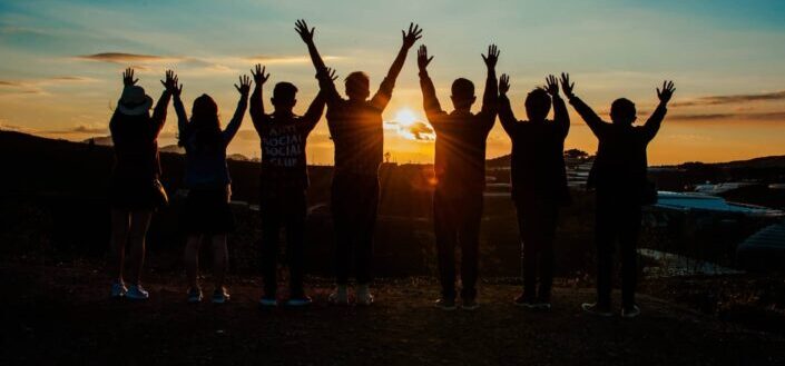 Silhouette of people raising hands