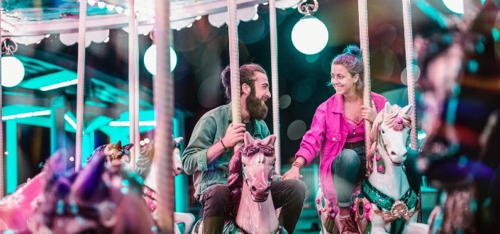 a couple smiling at each other while riding the carousel