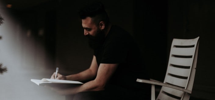 sitting man writing on his notebook