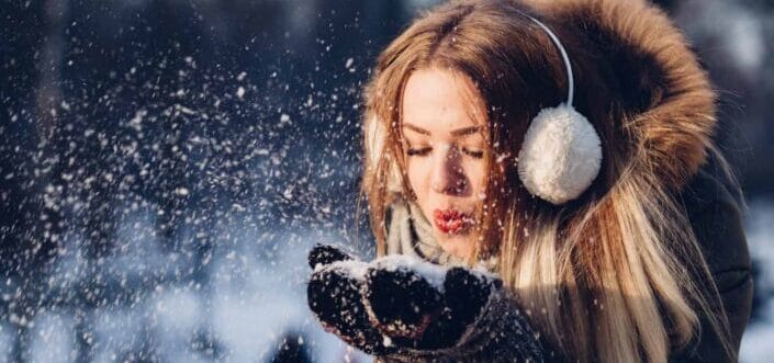 Woman blowing a handful of snow.