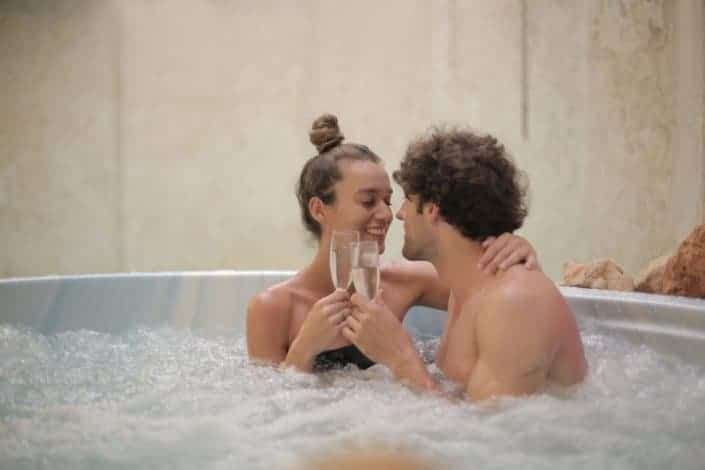 Couple intimately drinking wine in a jacuzzi.