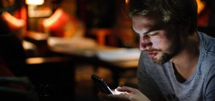 Man texting on his dim lighted room