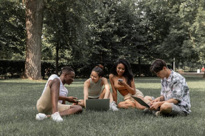 multiethnic-friends-with-gadgets-on-lawn-pexels