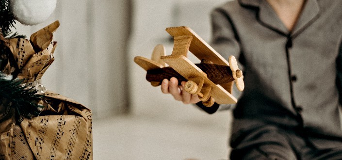 Boy in Pajamas Holding Brown Wooden Plane Toy