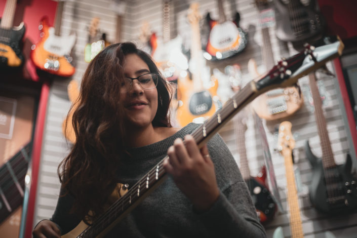 Woman playing bass in a guitar shop