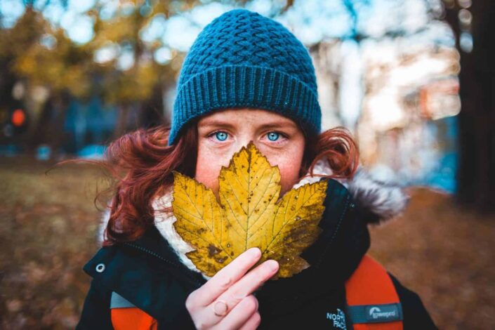 Girl in Knit Cap Holding Yellow Maple Leaf