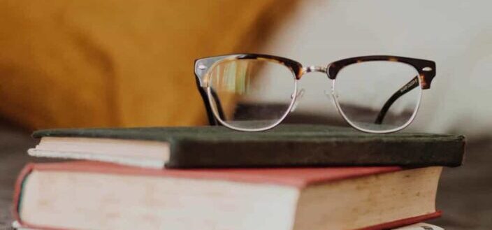 A reading glass laid on top of three books