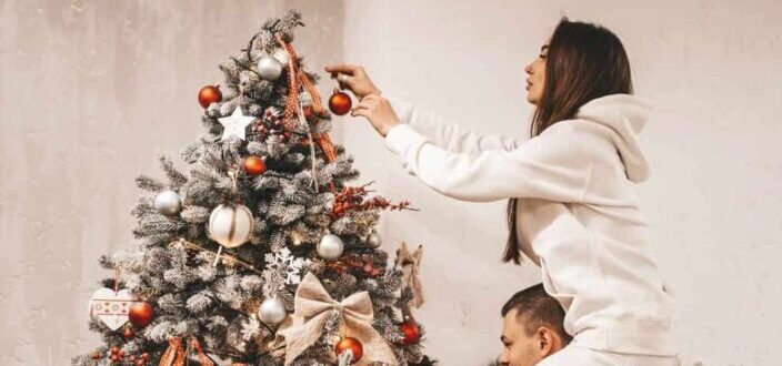 woman putting bauble on christmas tree