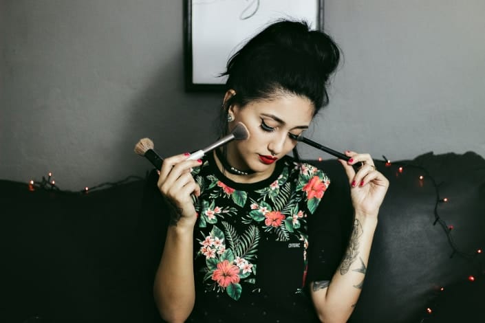 woman sitting on couch holding makeup brushes