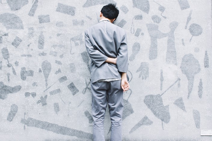 Man leans against gray wall