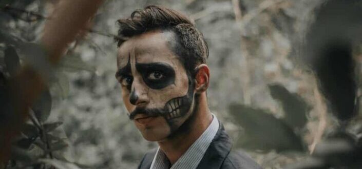 A man face-painted with skeleton drawing