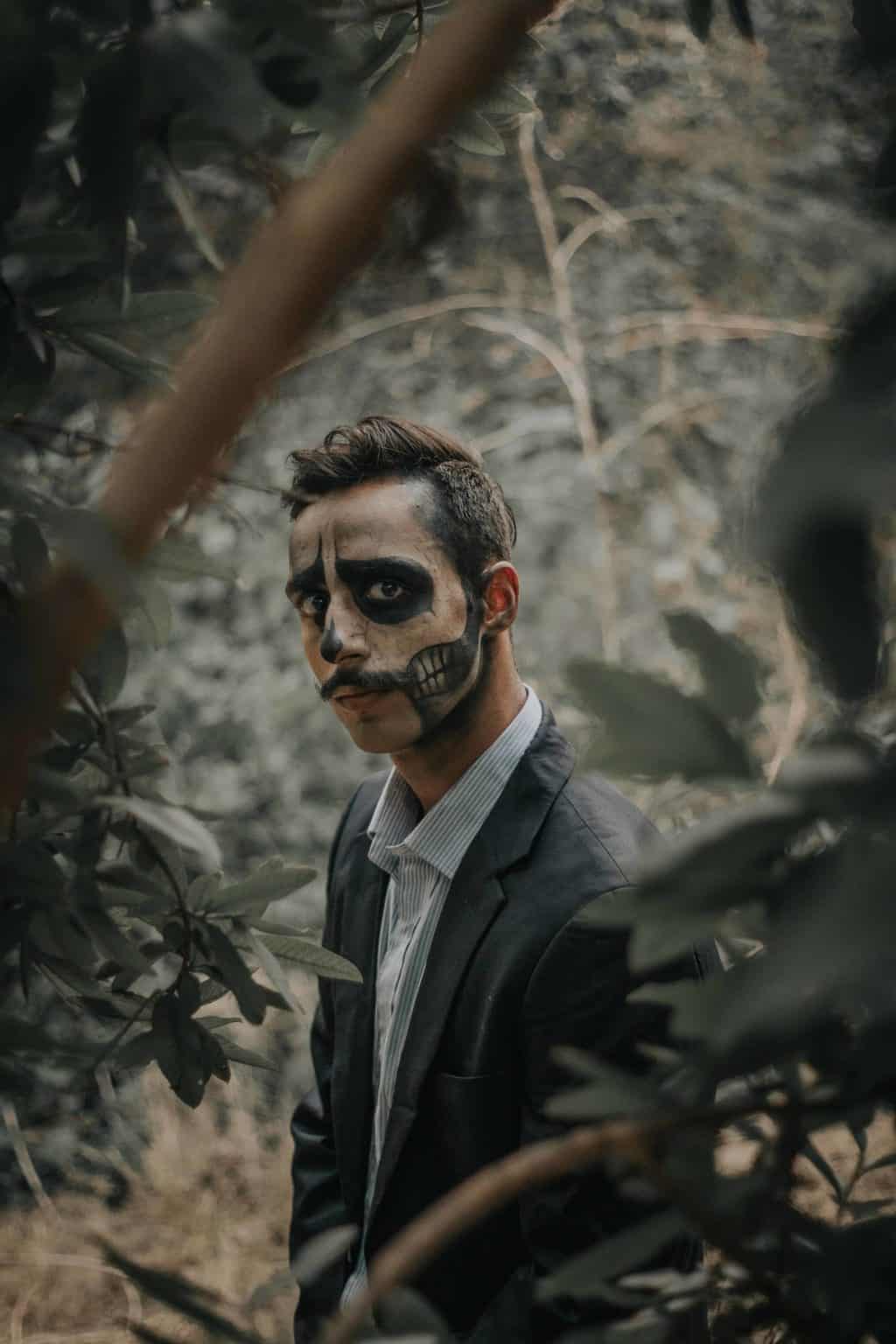 A man face-painted with skeleton drawing