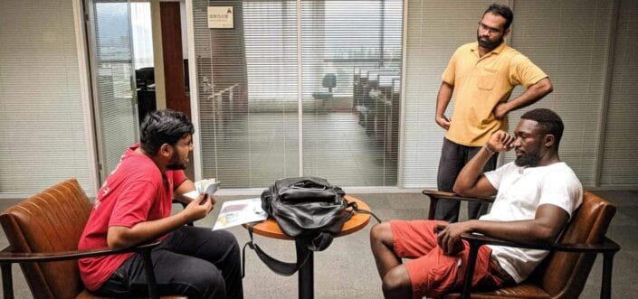 Three men talking to each other in a room.