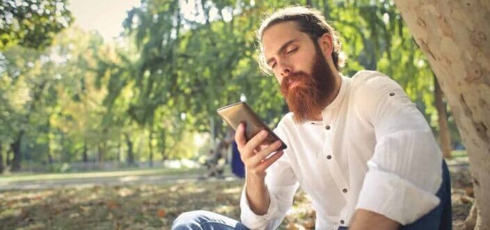 Bearded man checking his phone outdoors