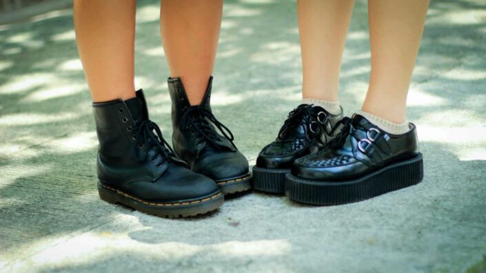 Two pairs of leather shoes worn by kids.