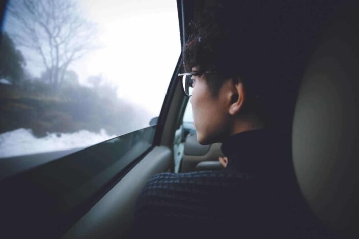 Guy sitting on a car seat, looking away.