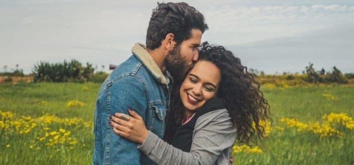 Couple hugging each other on a field.