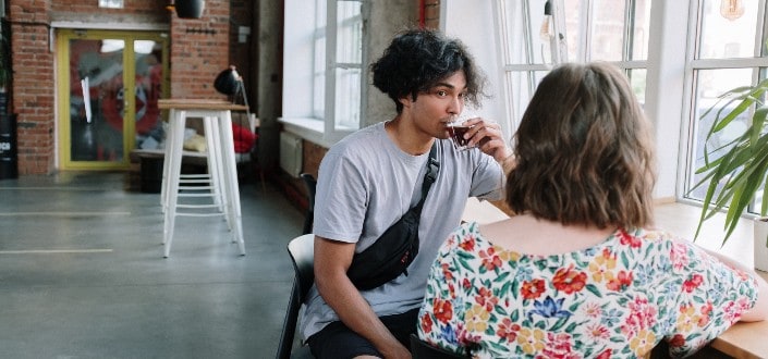 man staring at his girlfriend while drinking