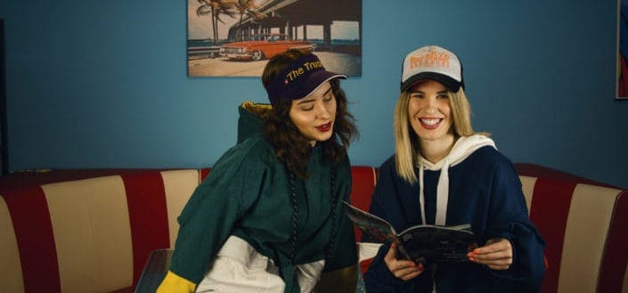 Two girl friends reading a magazine together.