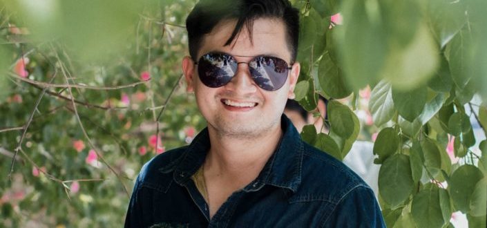 handsome smiling man in black leather jacket in front of city bridge.jpg