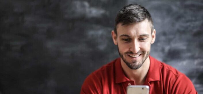 Man in Red Polo Shirt Holding Iphone