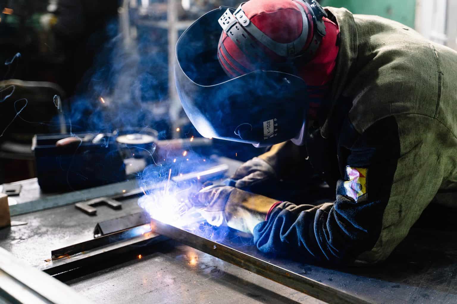 welder with a green jacket doing his work