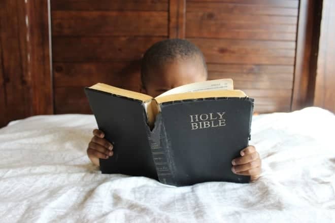 young kid reading the bible - bible trivia for kids