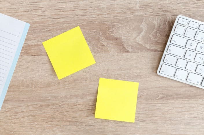two yellow sticky notes with notebook and keyboard on each side