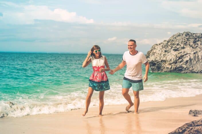 photo-of-laughing-couple-walking-by-the-beach-