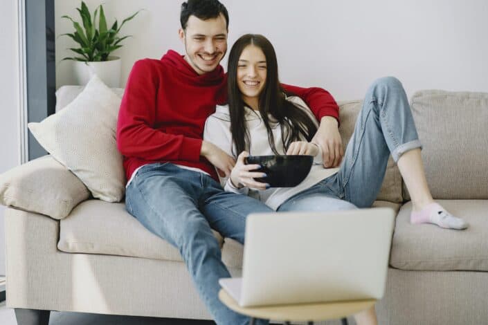 happy-couple-watching-movie-on-laptop-in-apartment