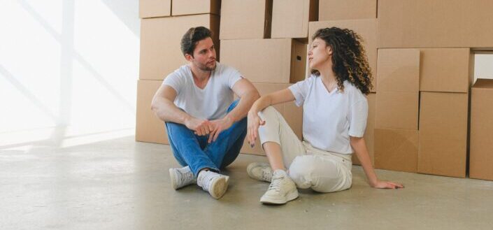 couple-conversing-against-heaps-of-boxes-during-relocation-