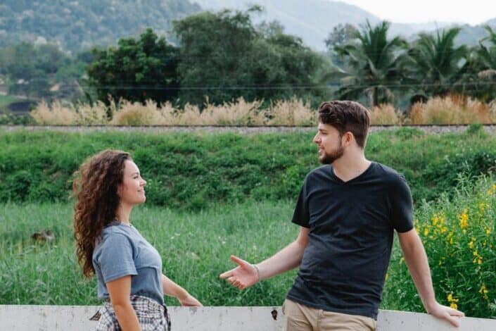 couple-standing-near-wooden-fence-and-communicating-in-nature-