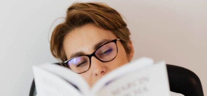 Young man wearing eyeglasses reading a book